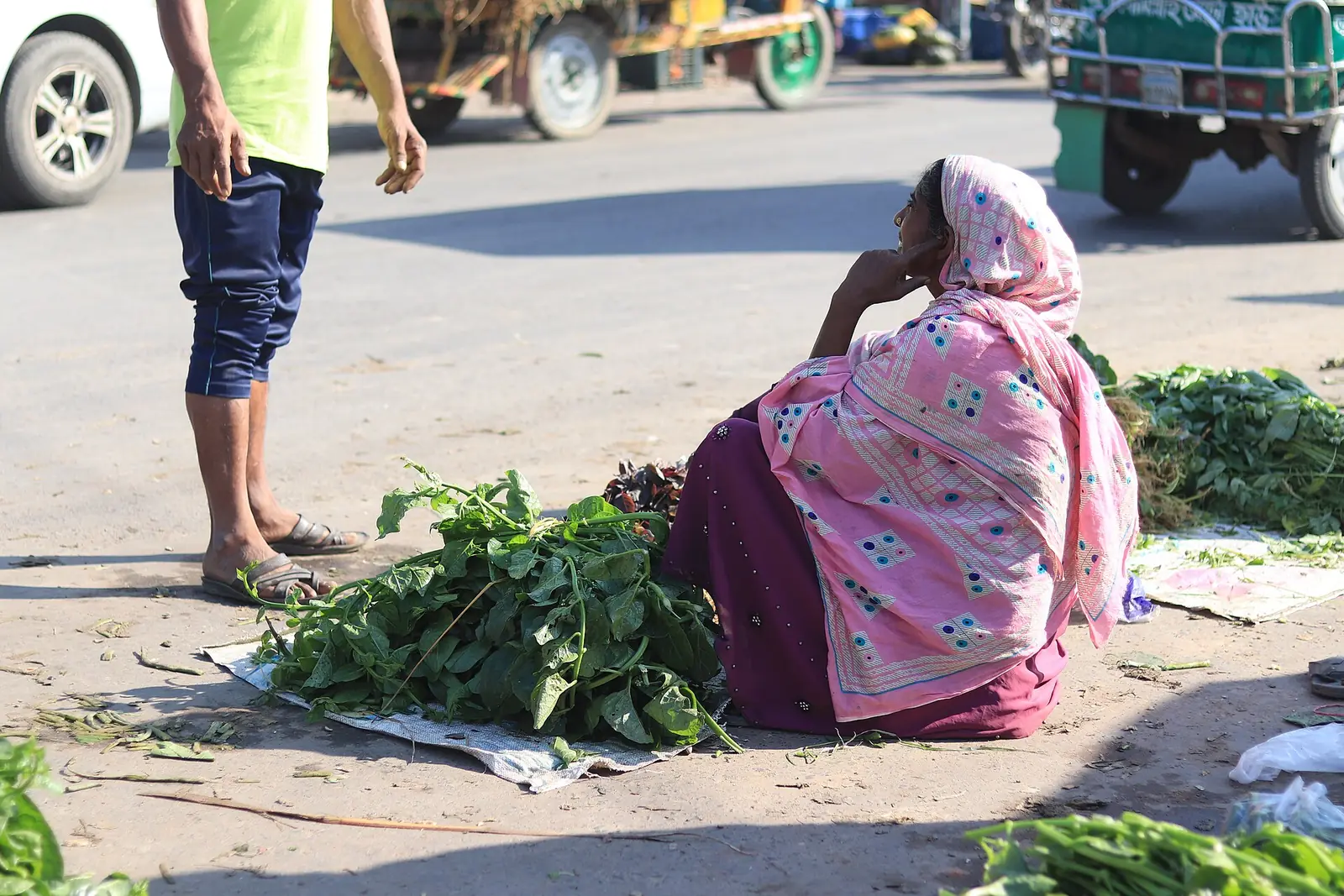 A woman selling leafy greens she grew herself at the local farmers' market in Rajshahi, Bangladesh.